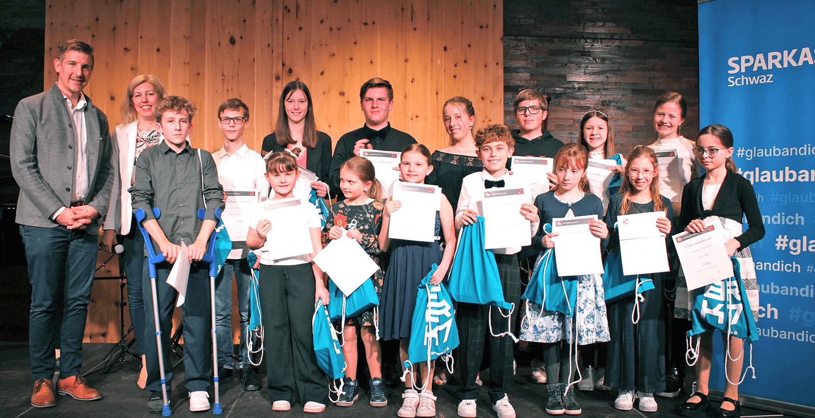 Alexander Lener (Marketingleiter Sparkasse Schwaz) mit Sonja Melzer (Landesmusikschule Schwaz) und den zahlreichen Musiktalenten beim regionalen Preisträgerkonzert im Feuerwerk Fügen.