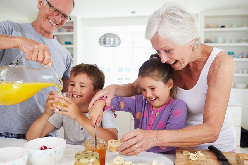 Grandparents With Grandchildren Making Breakfast In Kitchen