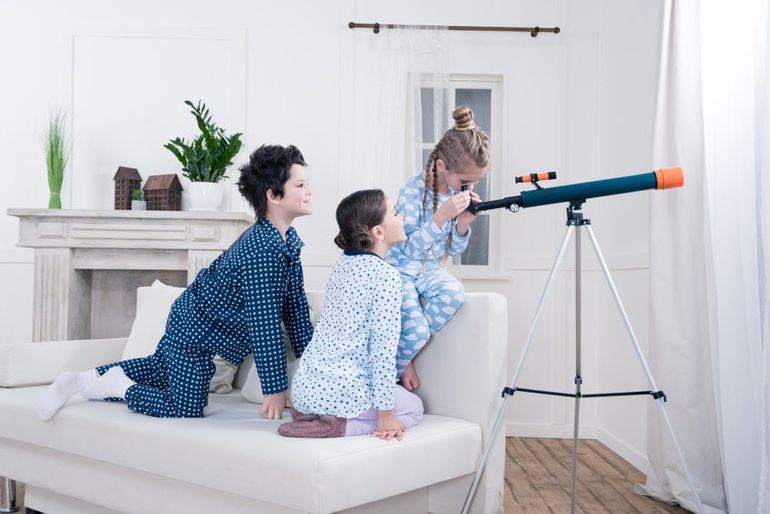 kids playing with telescope and looking out window