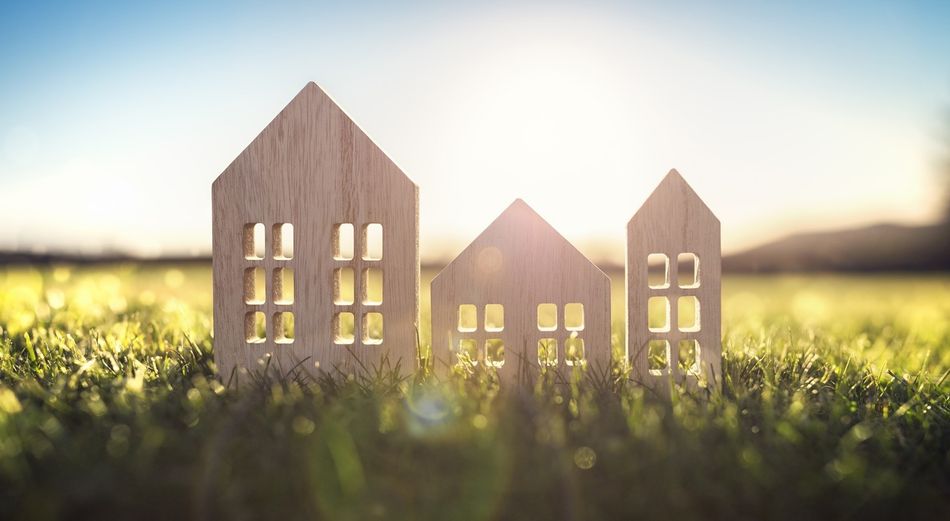 Holzhaus-Modell auf grüner Wiese im Sonnenuntergang