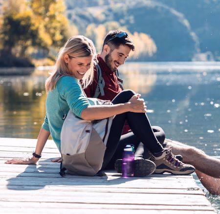 Two travel hikers in love enjoying the nature while playing with water in the lake of the mountain.