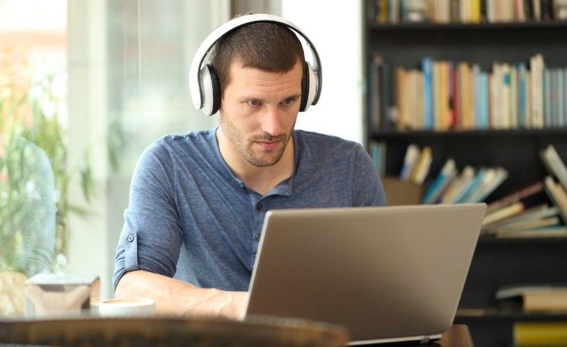 muž se sluchátky u notebooku
