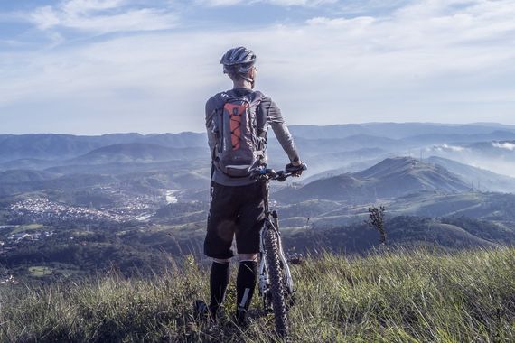 Cyklista na kopci hledí na krajinu