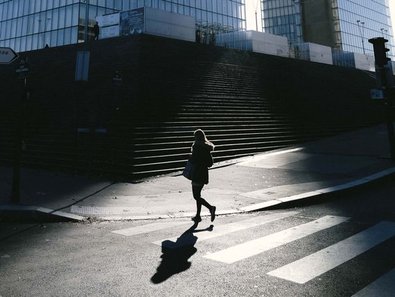 Žena přechází silnici před budovou