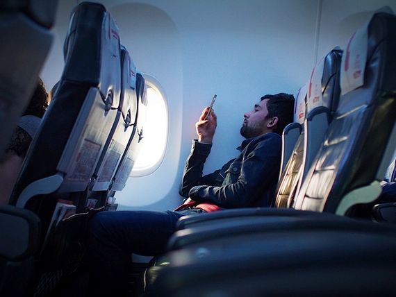 Cestující v letadle pracuje na mobilním telefonu