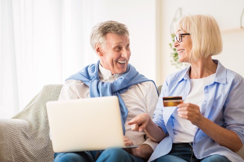 Happy mature couple making online purchases on laptop