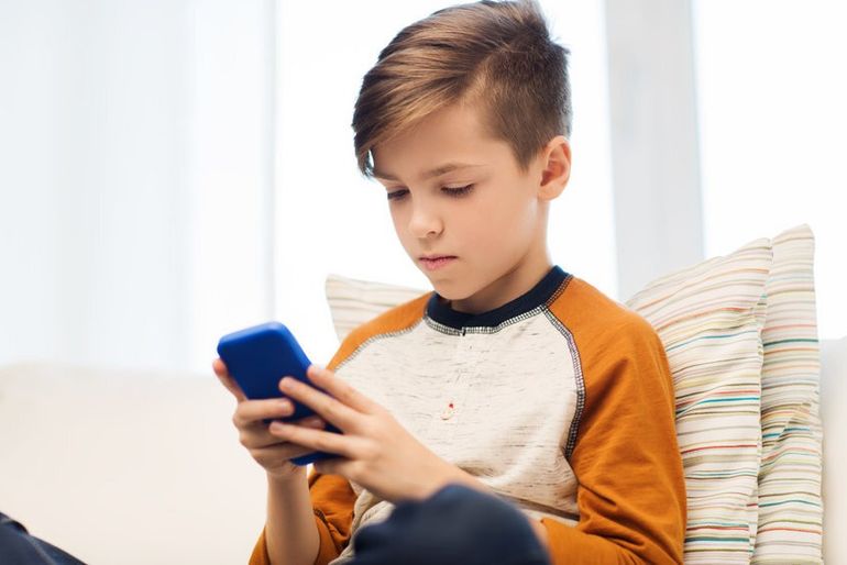 boy with smartphone texting or playing at home