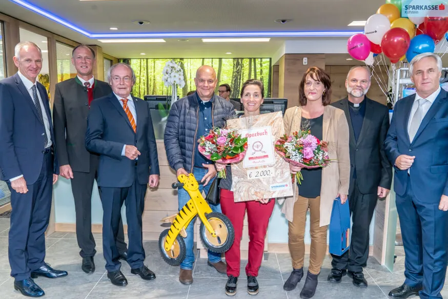 stehende Frauen mit Blumenstrauß in der Hand und nebenan Männer