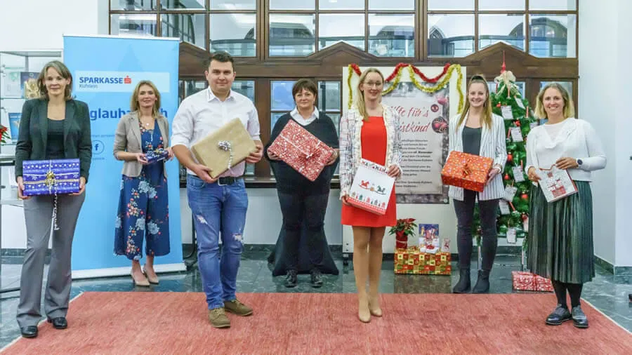 eine Gruppe von Menschen steht in einem Foyer und hält Geschenke