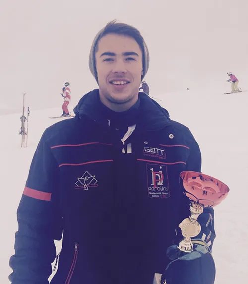 junger Mann mit Pokal auf der Ski-Piste