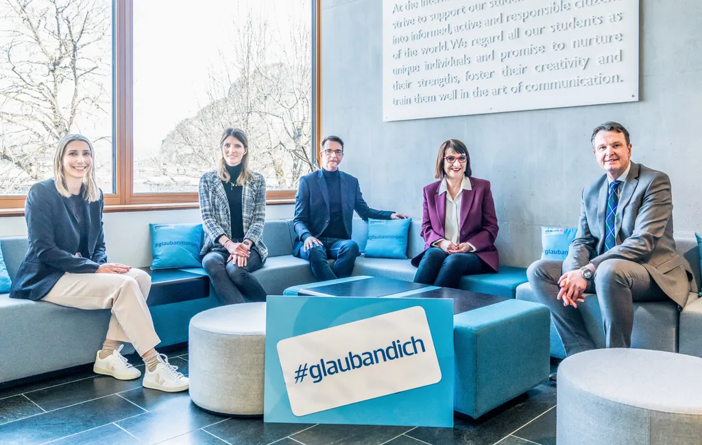 5 Personen sitzen auf einer Couch und lächeln in die Kamera