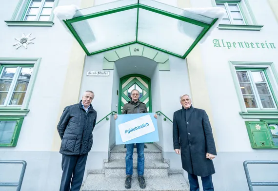 3 Herren posieren vor einem Gebäude