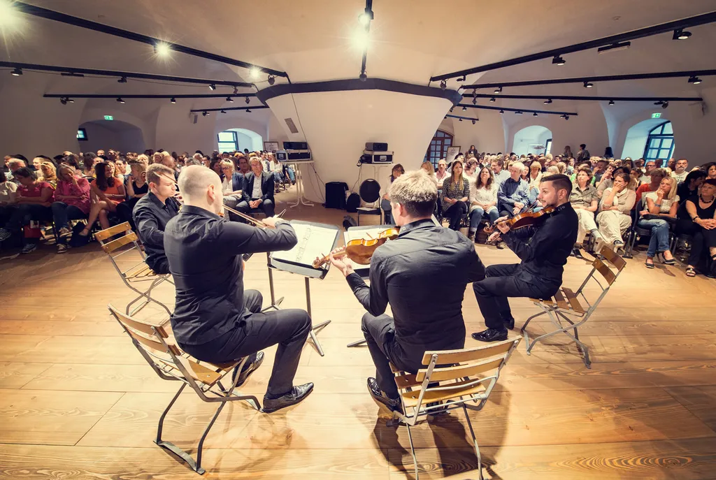 vier spielende Männer mit Geige vor Publikum