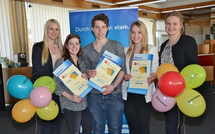 vier Frauen und ein Mann mit Sparbuch und Luftballon in der Hand