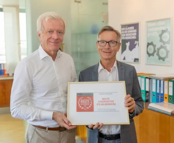 Zwei Männer halten eine Auszeichnung in der Hand