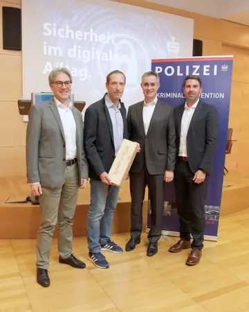 Peter Zoth (Kremser Bank), Robert Mayer, Christian Hager, Rene Matous (Kremser Bank) stehen nebeneinander im Ferdinand Dinstl Saal vor einem Bildschirm mit dem Text 'Sicherheit im digital Alltag' und einem Banner der Polizei mit dem Schriftzug 'POLIZEI KRIMINALPRÄVENTION'