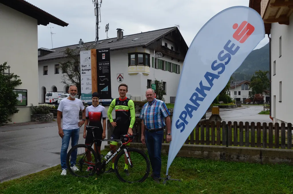 4 Personen, zwei davon in Sportkleidung mit Fahrrad stehen im Freien und lächeln in die Kamera