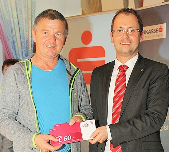 zwei Männer halten gemeinsam einen Gutschein in der Hand 