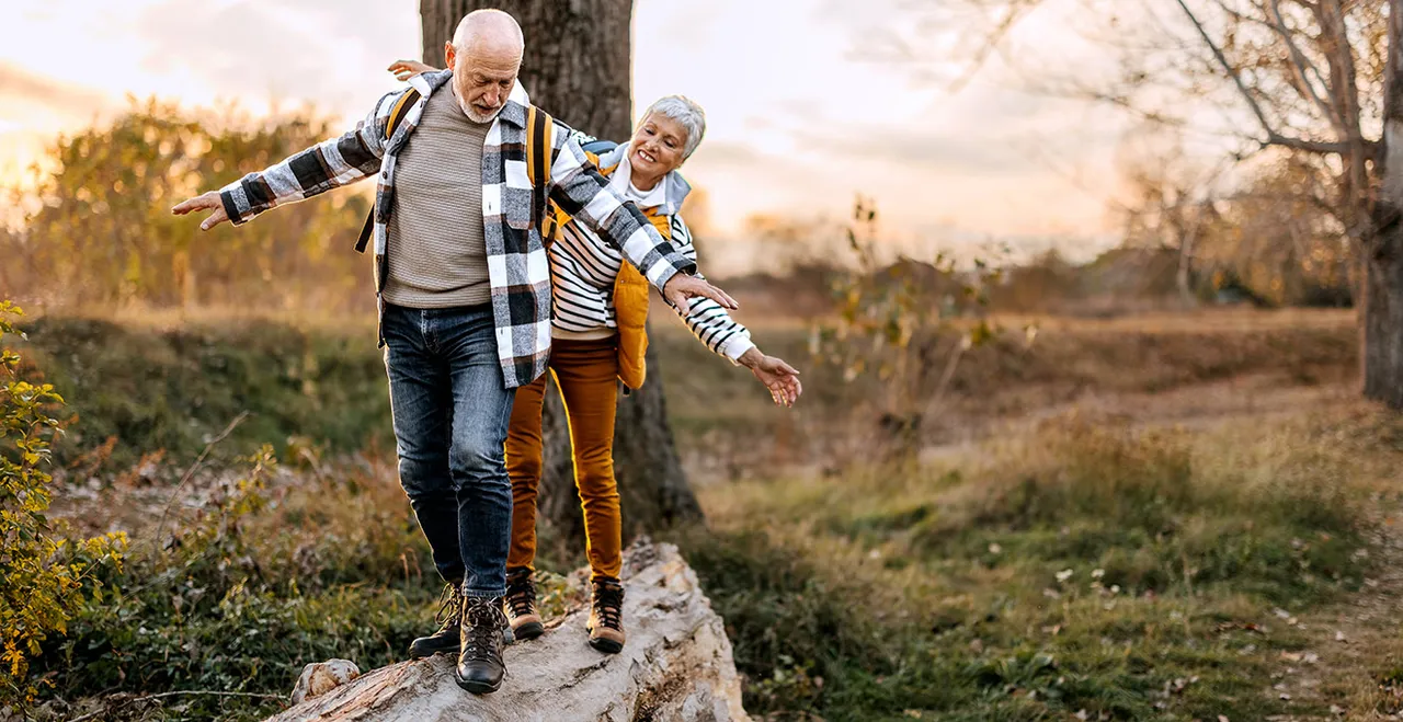 Älteres Ehepaar balanciert auf einem Baumstamm