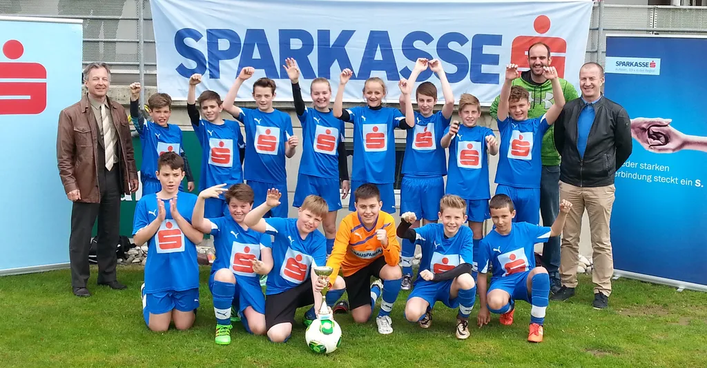 viele Kinder bei Fußballspiel mit Hände in der Höhe und Pokal in der Hand