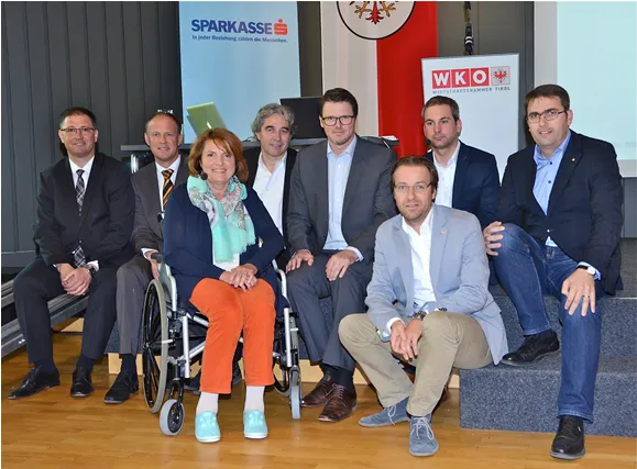 eine Frau im Rollstuhl und sieben Männer sitzend 