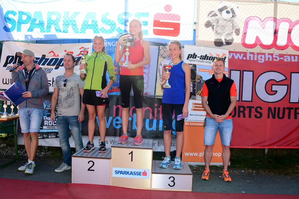 drei Frauen mit Pokal in der Hand auf Siegerpodest