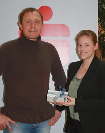 eine Frau hält ein Geschenk in der Hand und ein Mann steht nebenan 