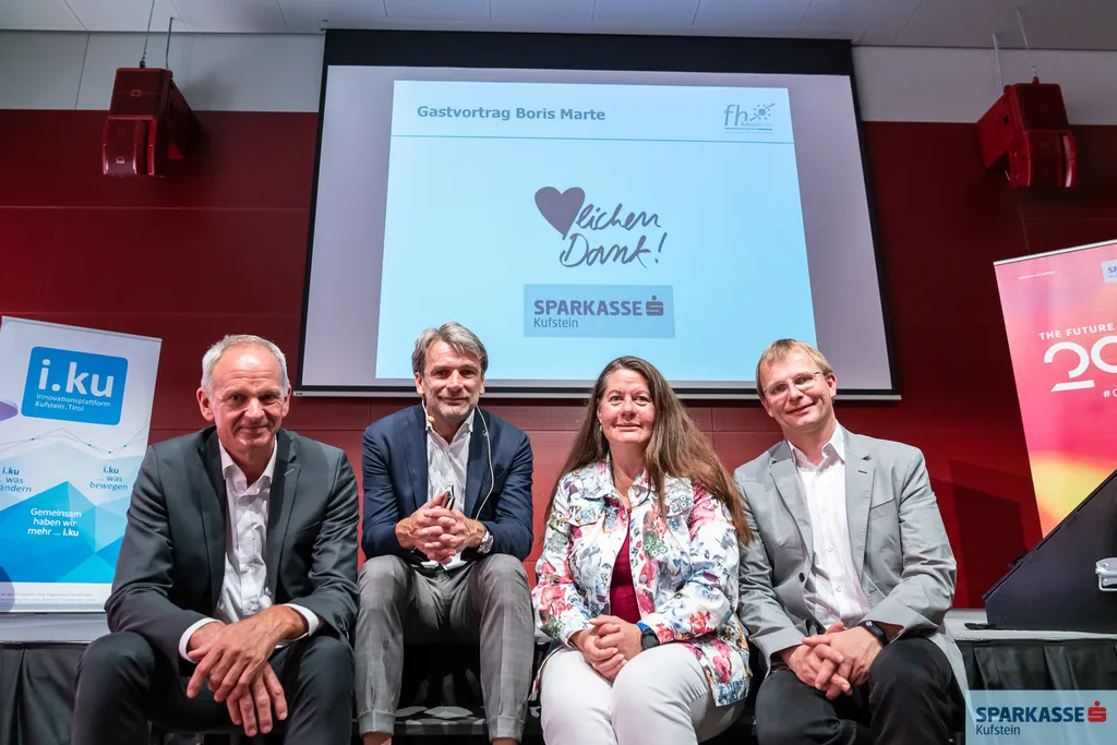 vier Personen lachen sitzend in die Kamera