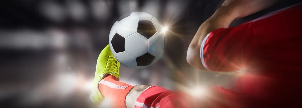 Nahaufnahme des Fußes eines Fußballspielers, der den Ball tritt