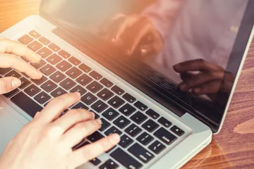 Männerhände tippen auf einem Laptop