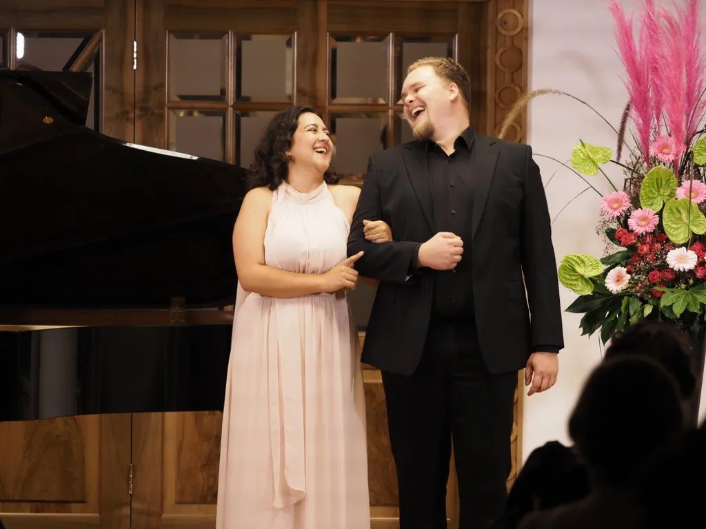 Dame und Herr in Abendkleidung eingehakt lachen einander an