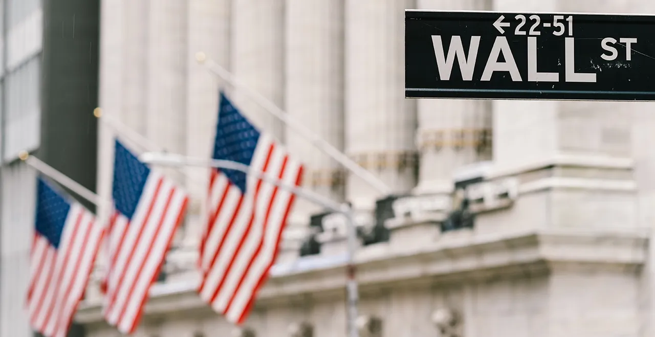 US-Flaggen und ein Wegweiser mit der Aufschrift Wall St.