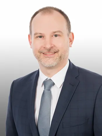 Herr mit grauer Krawatte lächelt in die Kamera