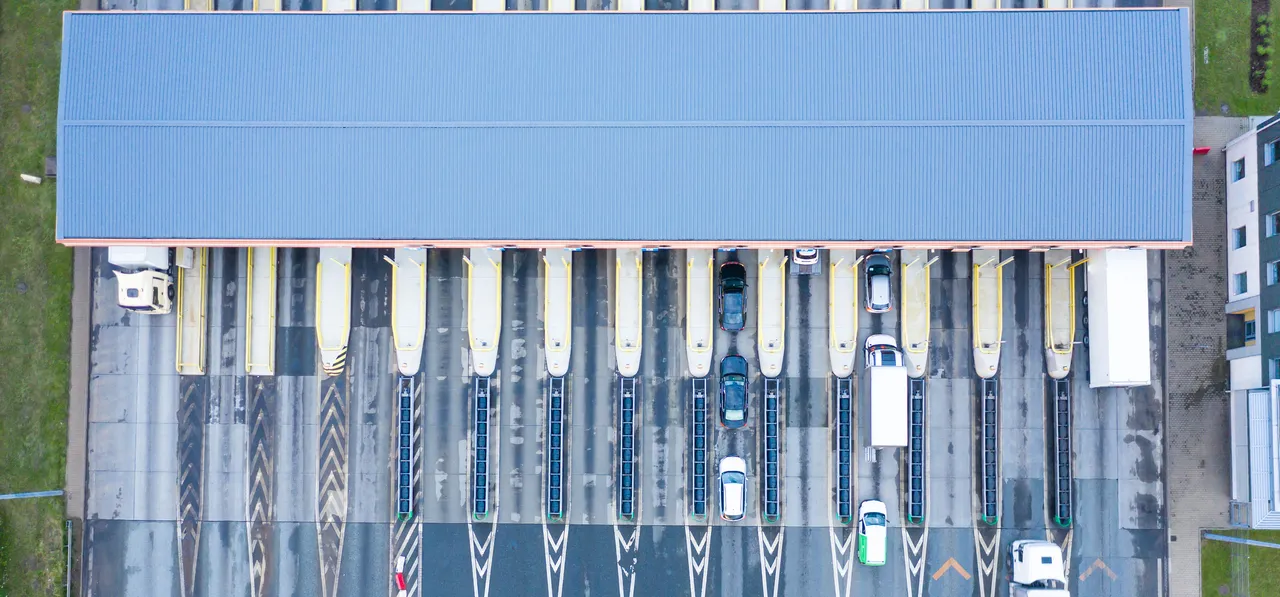 Autoverkehr auf einer mehrspurigen Autobahn mit Mautstation, aus der Vogelperspektive mit Drohne aufgenommen.