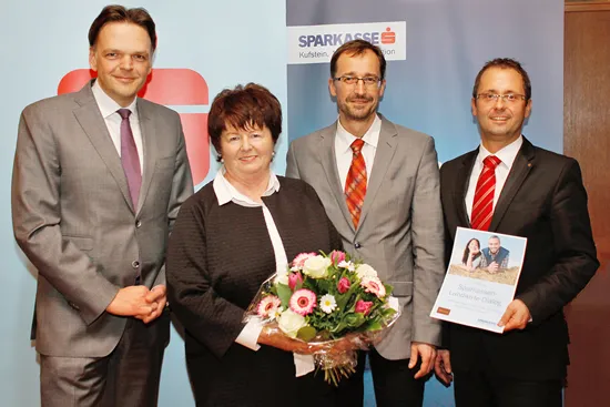 eine Frau hält Blumen in der Hand un drei Männer stehen nebenan 