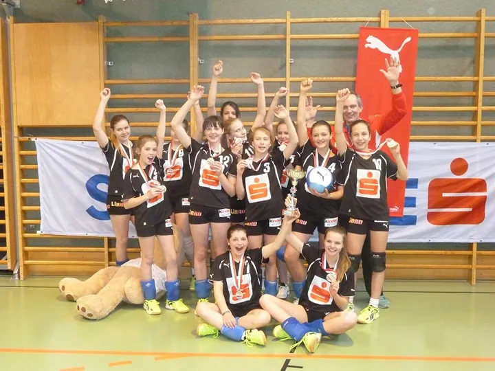 Gruppenbild von Mädchen mit Volleyball und Pokal in der Hand 