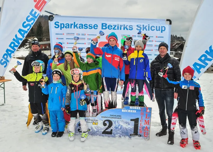 viele Kinder im Skianzug mit Pokal in der Hand