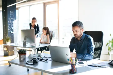 Drei Menschen arbeiten in einem Büro am Schreibtisch