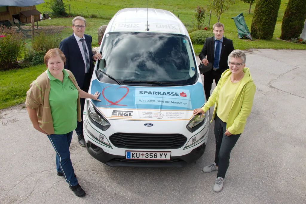 4 Personen stehen um ein Auto, das einen Sparkasse Aufkleber hat