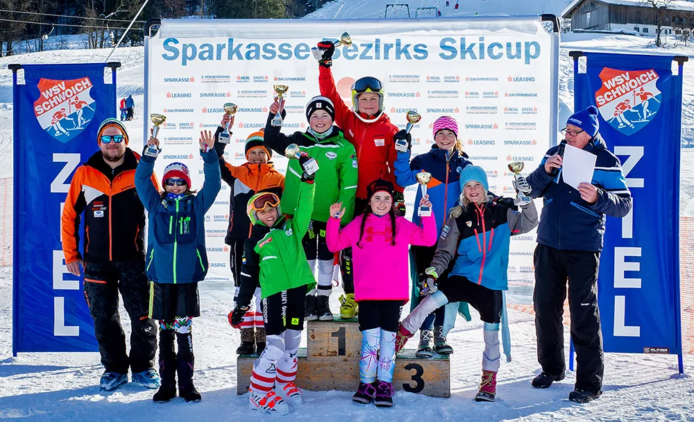 Kinder nach Skirennen jubeln mit Pokal in der Hand