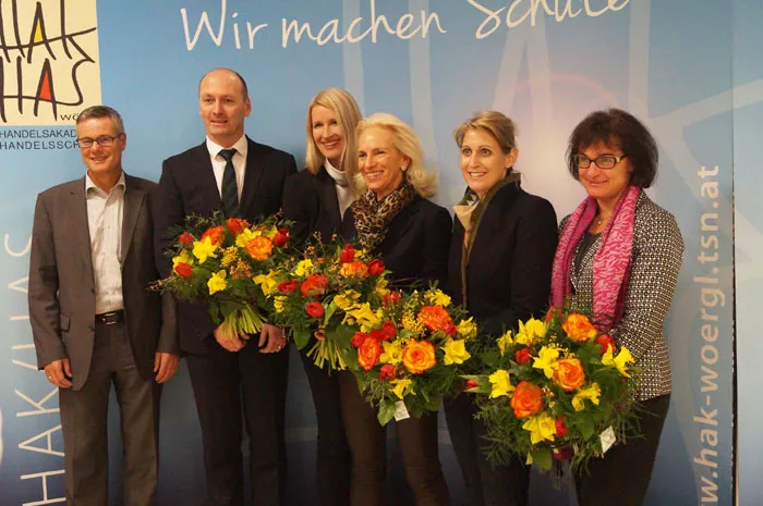 Eine Gruppe von Menschen lacht in die Kamera, die Damen halten Blumensträuße in den Händen