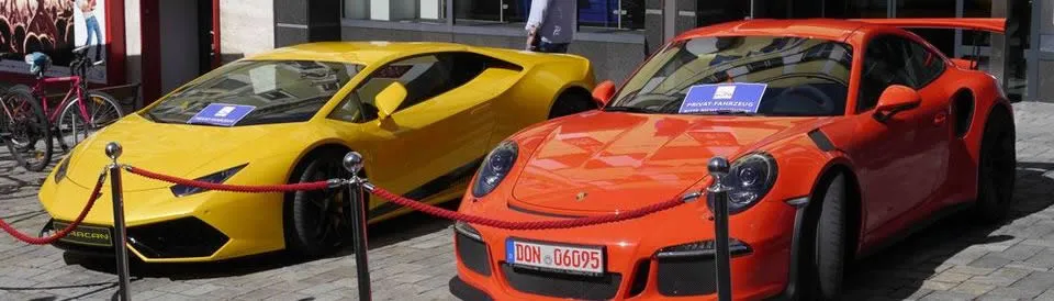 ein gelber Lamborghini und ein orangener Porsche stehen nebeneinander 