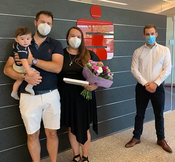 Kundenbetreuer Marcus Lechner (rechts) übergibt den glücklichen Gewinnern Kristina und Patrick Danzl ihren Hochzeitsreise-Gutschein in der Sparkassen-Filiale Gloggnitz. Auch der kleine Philipp freut sich für seine Eltern.