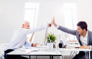 Kollegen, im Büro, geben sich High Five.