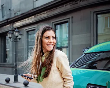 Frau hält Schlüsselbund eines neu gekauften Autos auf dem Parkplatz im Freien