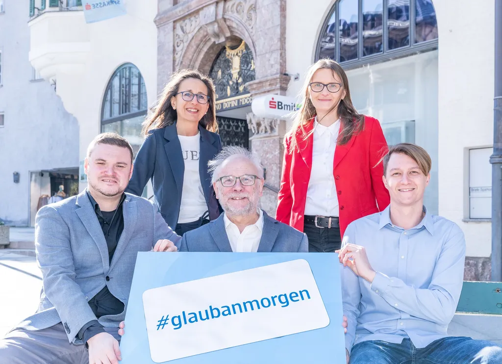 5 Personen stehen und sitzen im Freien und halten das #glaubandich Schild in die Kamera
