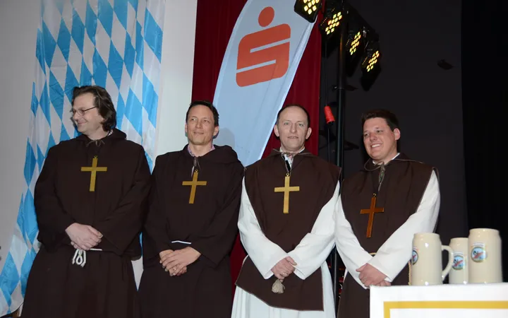 vier Männer mit Kreuz über dem Hals stehen auf der Bühne