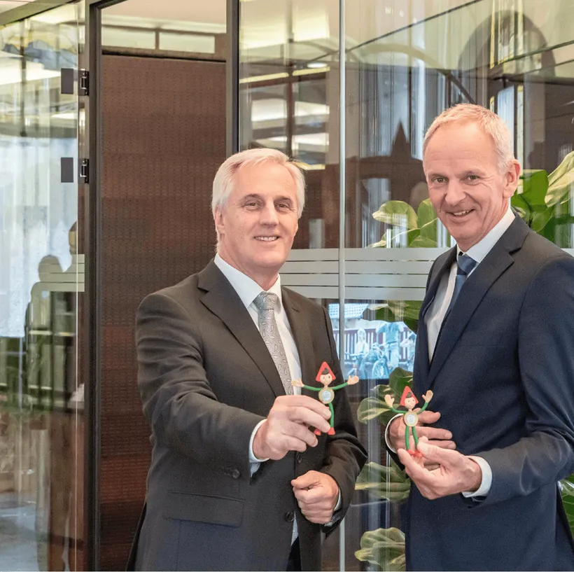 zwei Männer zeigen Sparkasse Maskottchen in die Kamera