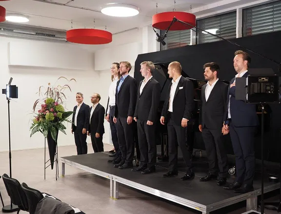 Herren in schwarzen Anzügen stehen auf der Bühne