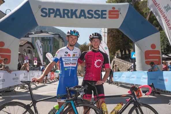 zwei Rennradfahrer stehend vor dem Zielbogen